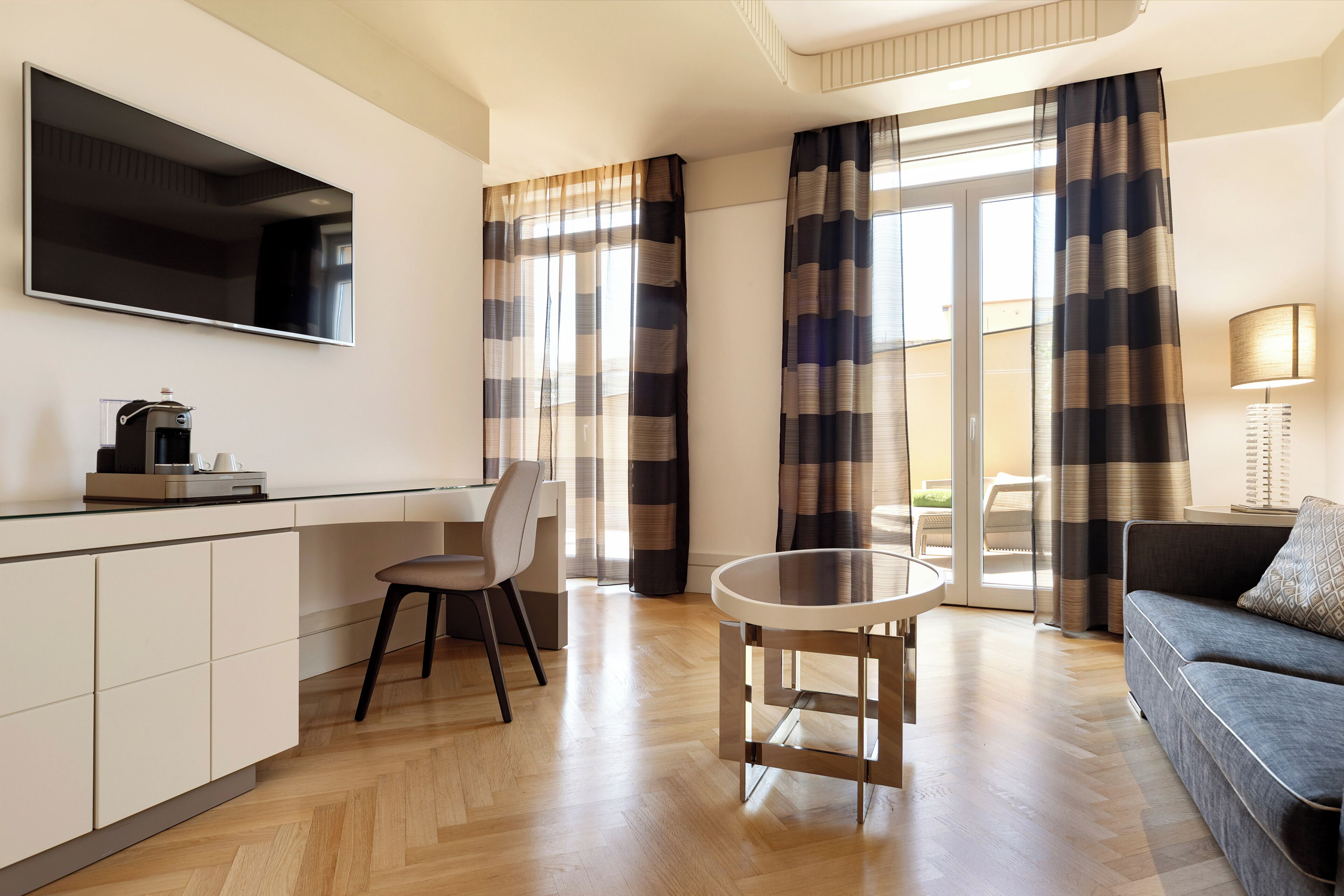 Una sala moderna con un sofá, una mesa de centro, un televisor montado en la pared y un área de comedor con una silla y una mesa.