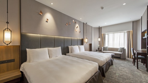 A hotel room with two beds, a sofa, a desk, and a chair. - Howard Prince Hotel Taichung (Taichung)