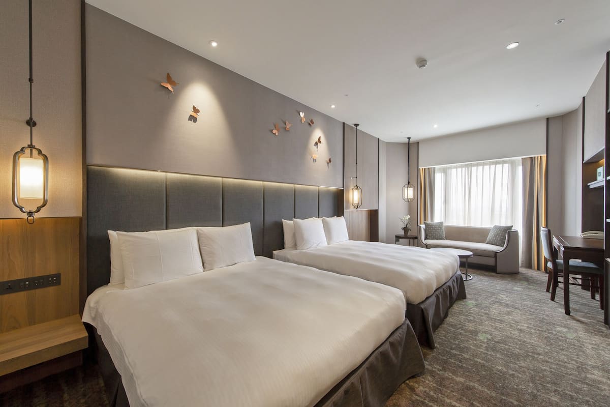Una habitación de hotel con dos camas, un sofá, un escritorio y una silla.