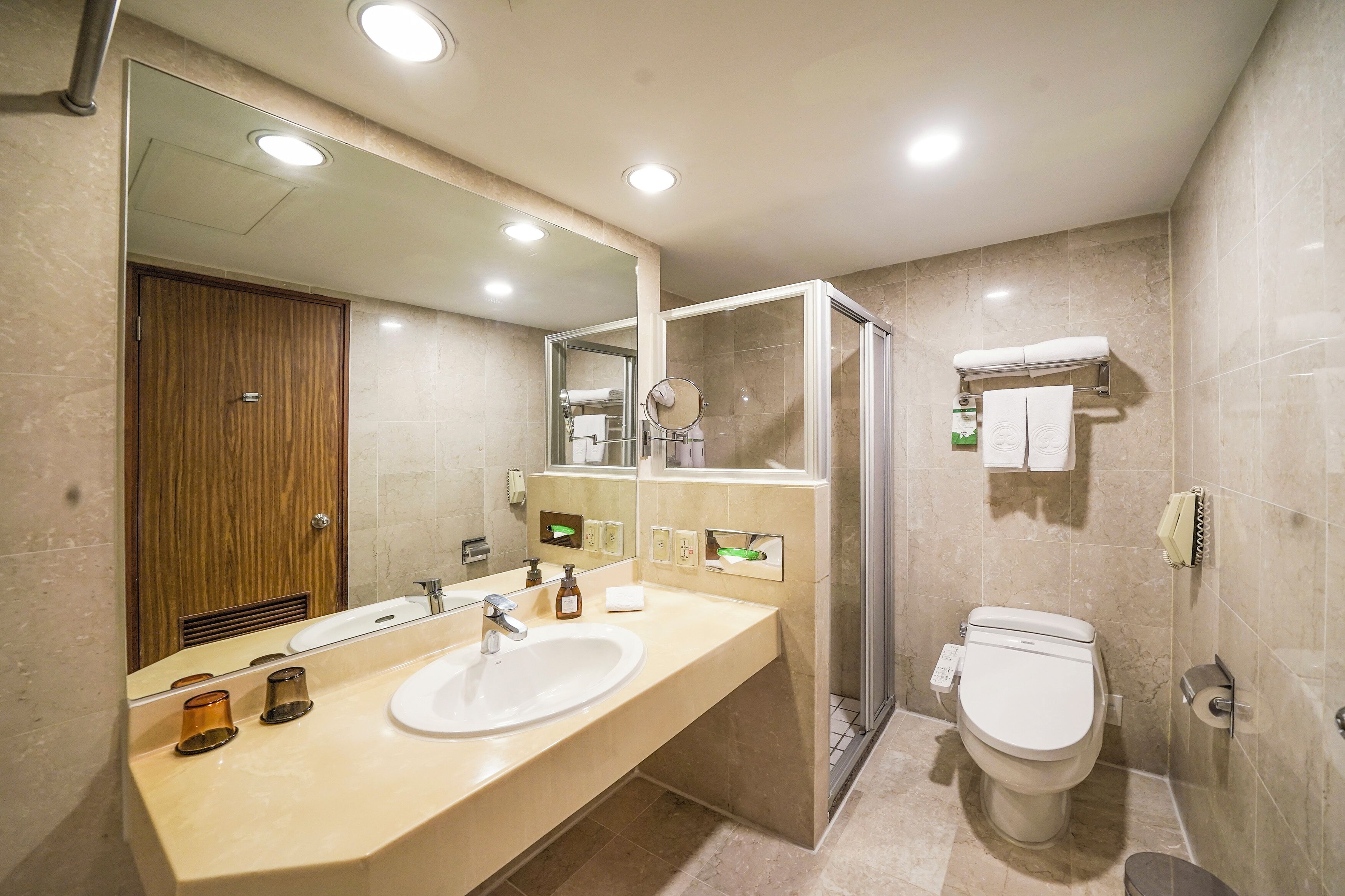 Un baño moderno con un espejo grande, un lavamanos, un inodoro y una ducha.