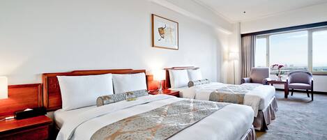 Ein Hotelzimmer mit zwei Betten, einem Schreibtisch und einem Sessel.