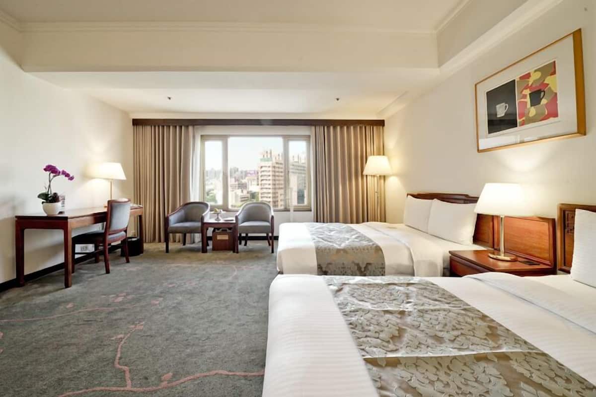Habitación de hotel con una cama, dos sillas, un escritorio y una ventana con cortinas.