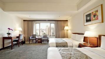 Habitación de hotel con una cama, dos sillas, un escritorio y una ventana con cortinas.