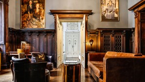 A room with a wooden floor, a leather sofa, a round wooden table, and a white door with decorative panels. - Villa Laetitia (Rome)