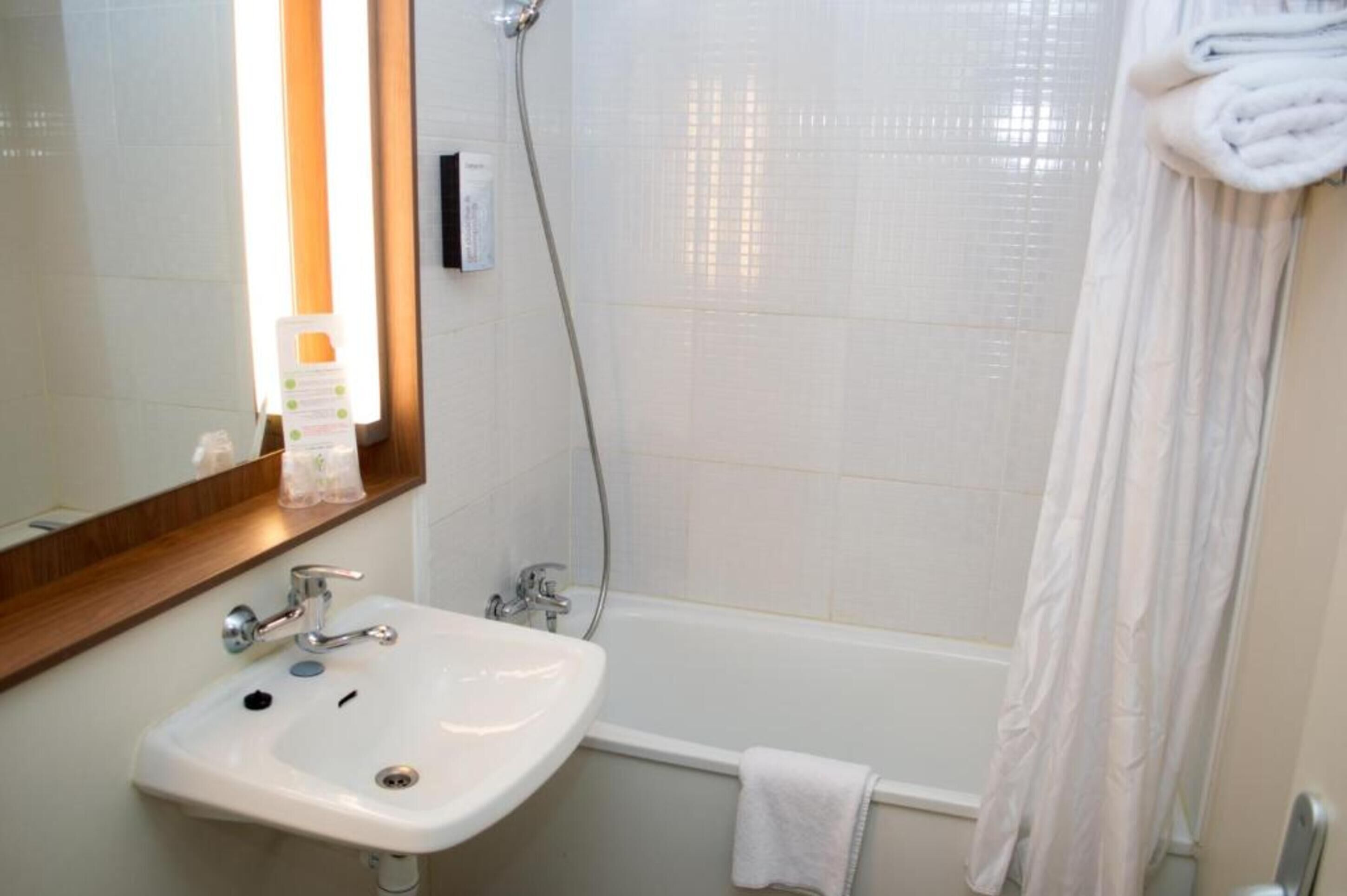 A bathroom with a white sink, mirror, and shower curtain.