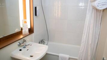 A bathroom with a white sink, mirror, and shower curtain.
