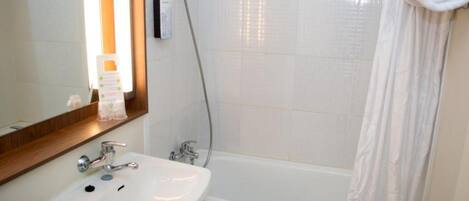 A bathroom with a white sink, mirror, and shower curtain.