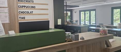 A modern coffee shop interior with a menu board listing espresso, double, macchiato, cappuccino, chocolate, and tea.