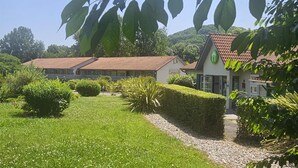 A traditional building with a tiled roof, surrounded by well-maintained hedges and a grassy lawn. - Campanile Villeneuve sur Lot - Pujols (Pujols)