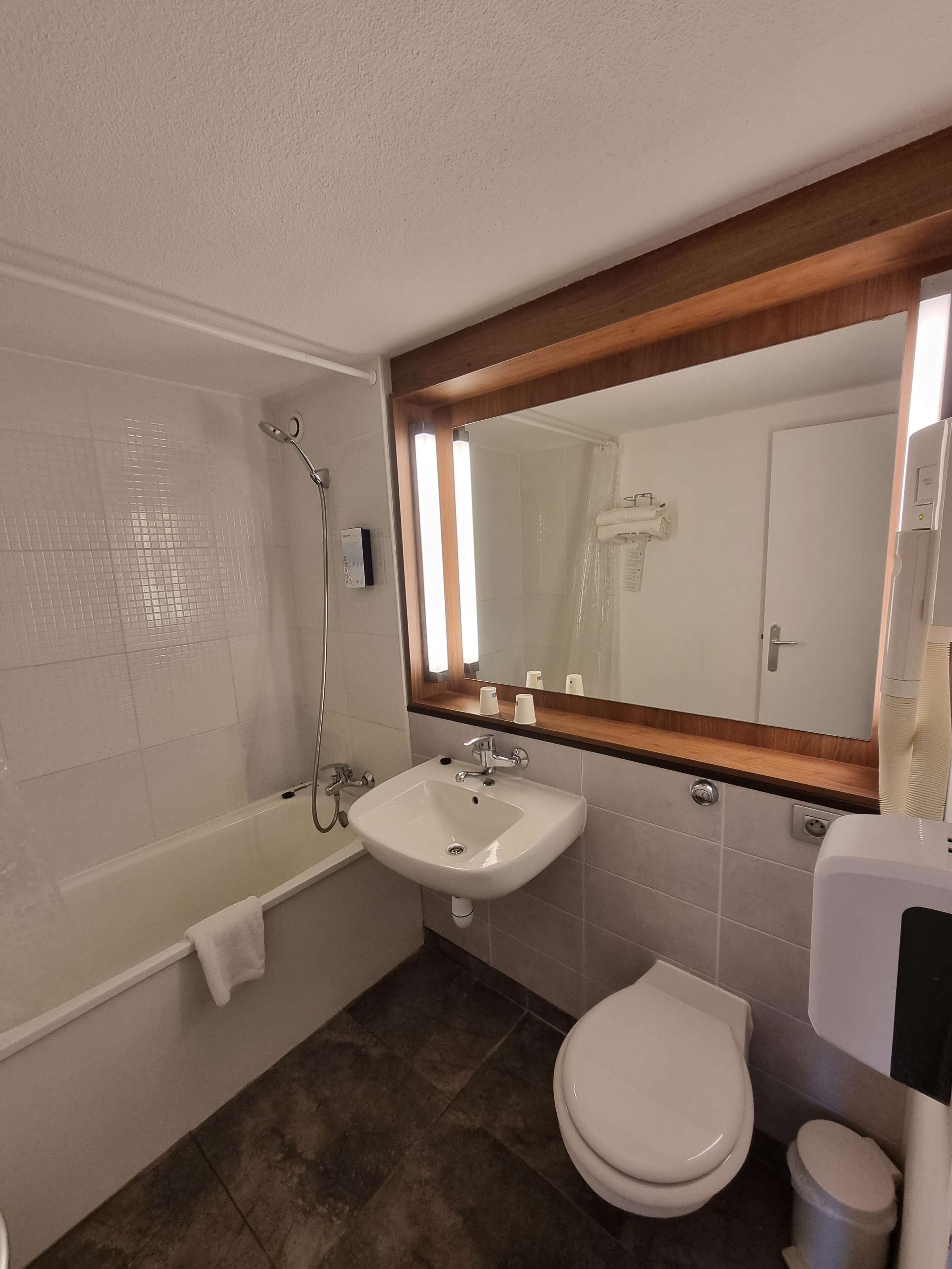 A bathroom with a bathtub, sink, toilet, and a mirror.