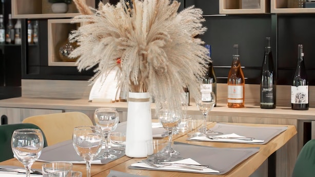 A dining area with a wooden table set for a meal, surrounded by chairs. - Campanile Villeneuve sur Lot - Pujols (Pujols)
