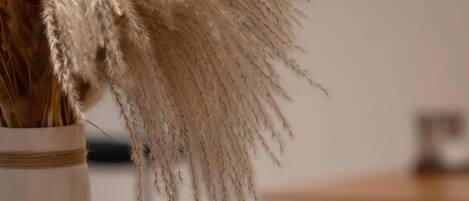 A breakfast setting with a plate of croissants, a glass of orange juice, and a vase with dried pampas grass.