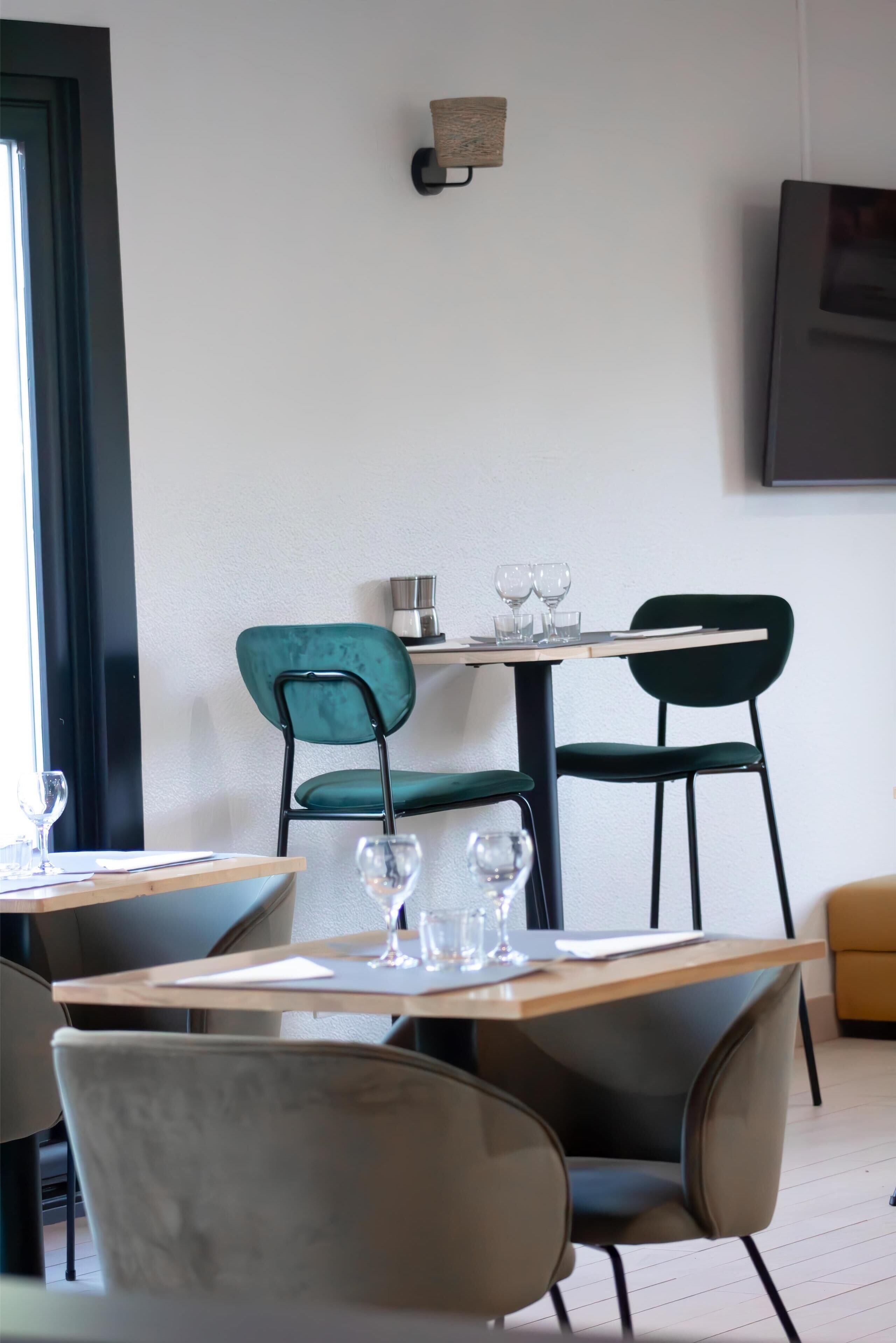A dining area with a table set for two, two chairs, and a wall-mounted coffee machine.