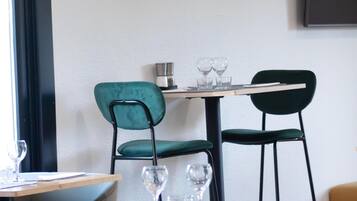 A dining area with a table set for two, two chairs, and a wall-mounted coffee machine.