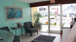 A hotel reception area with a reception desk, seating area, and a large window with a view of the street.