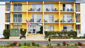A yellow multi-story motel with balconies, a visible American flag, and a sign indicating an open inn office.