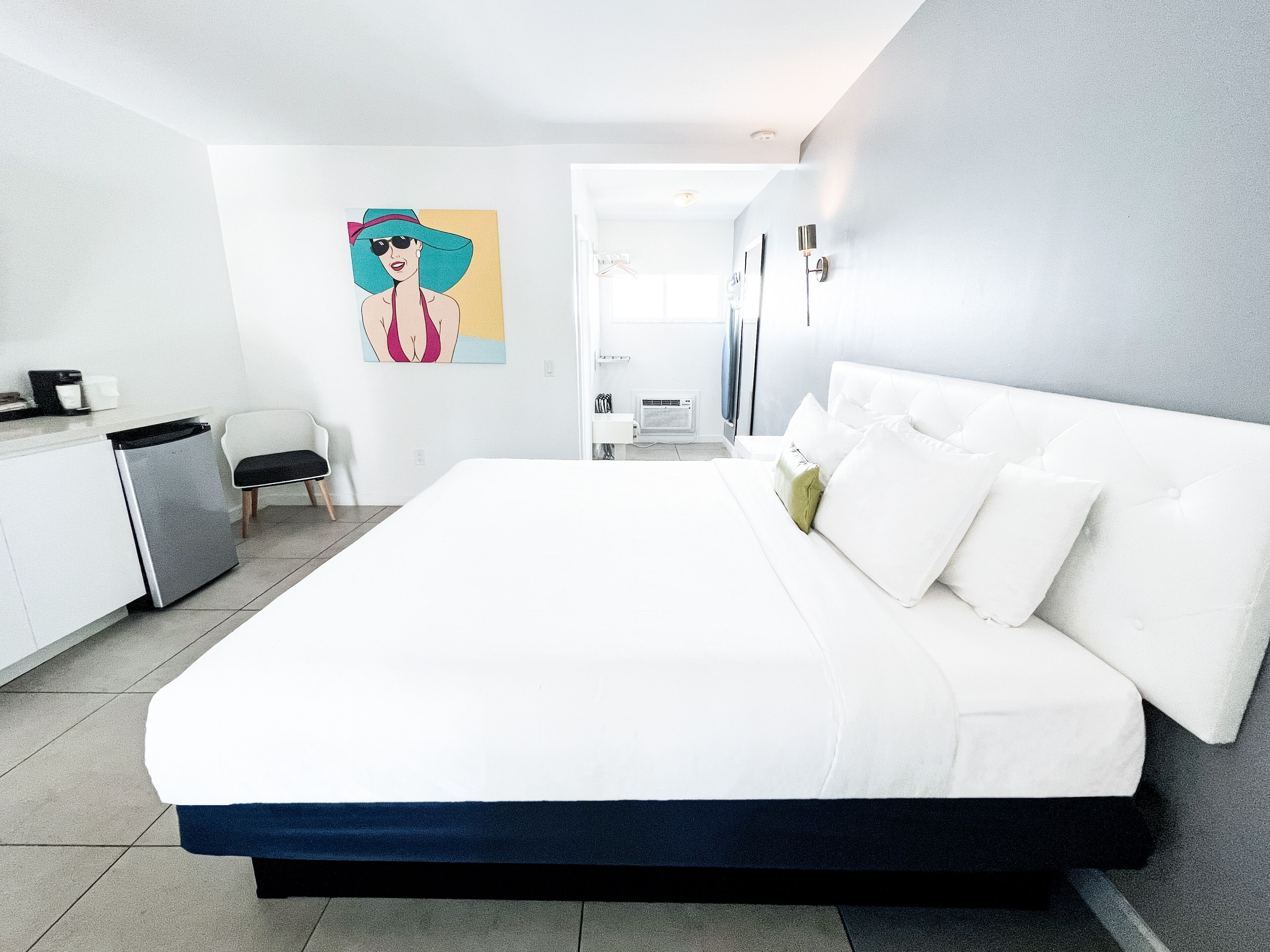 A modern hotel room with a large bed, a desk, and a chair.