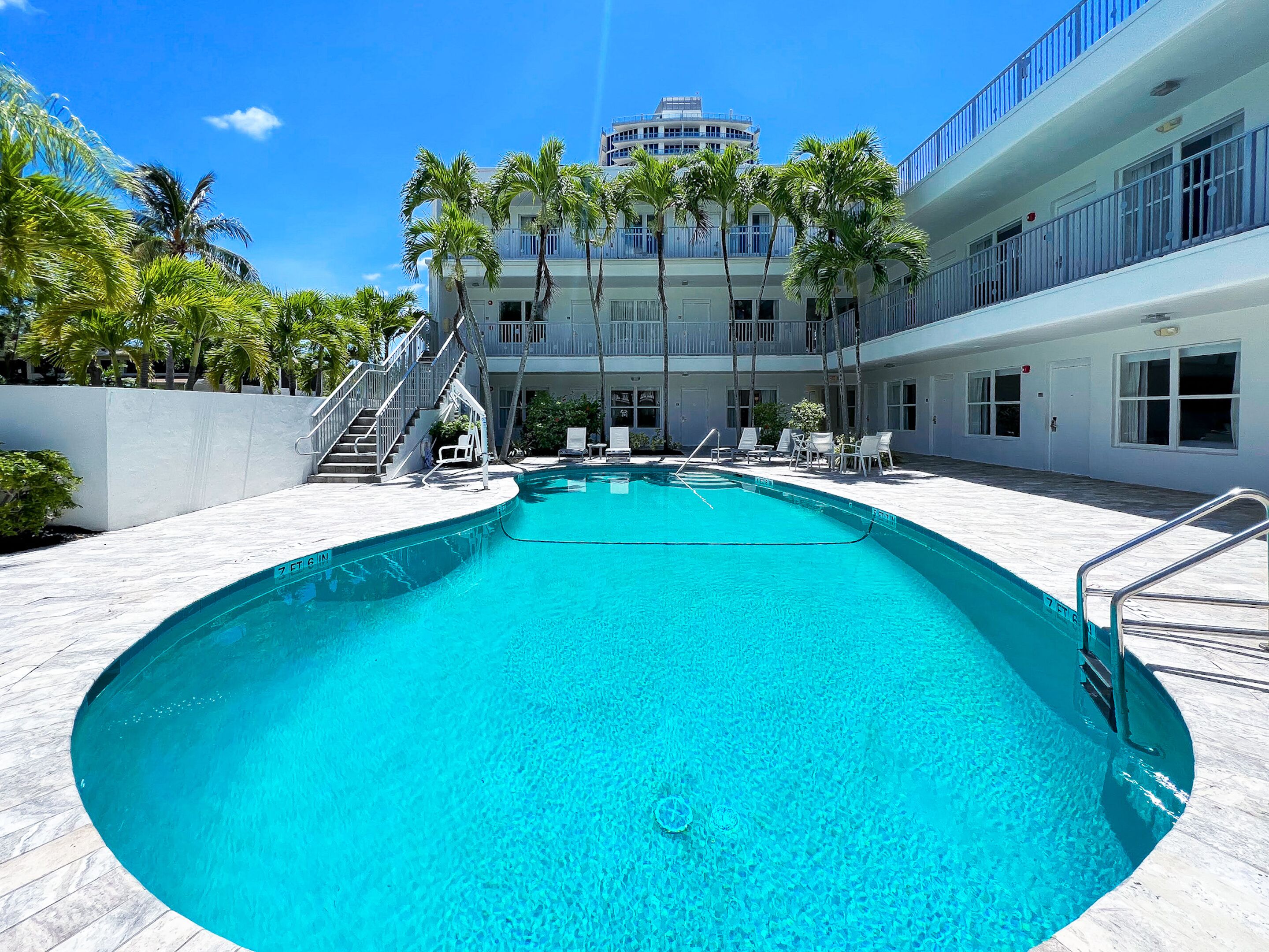 Une piscine à l’eau d’un bleu cristallin, entourée de chaises longues et de palmiers.