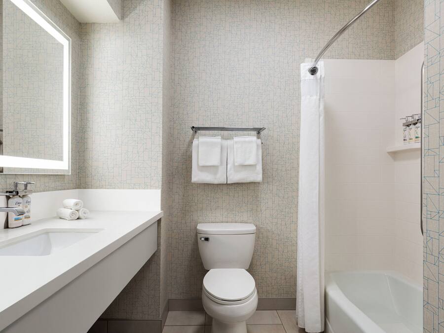 A bathroom with a white sink, toilet, and bathtub. There are two towels hanging on a rack above the toilet.