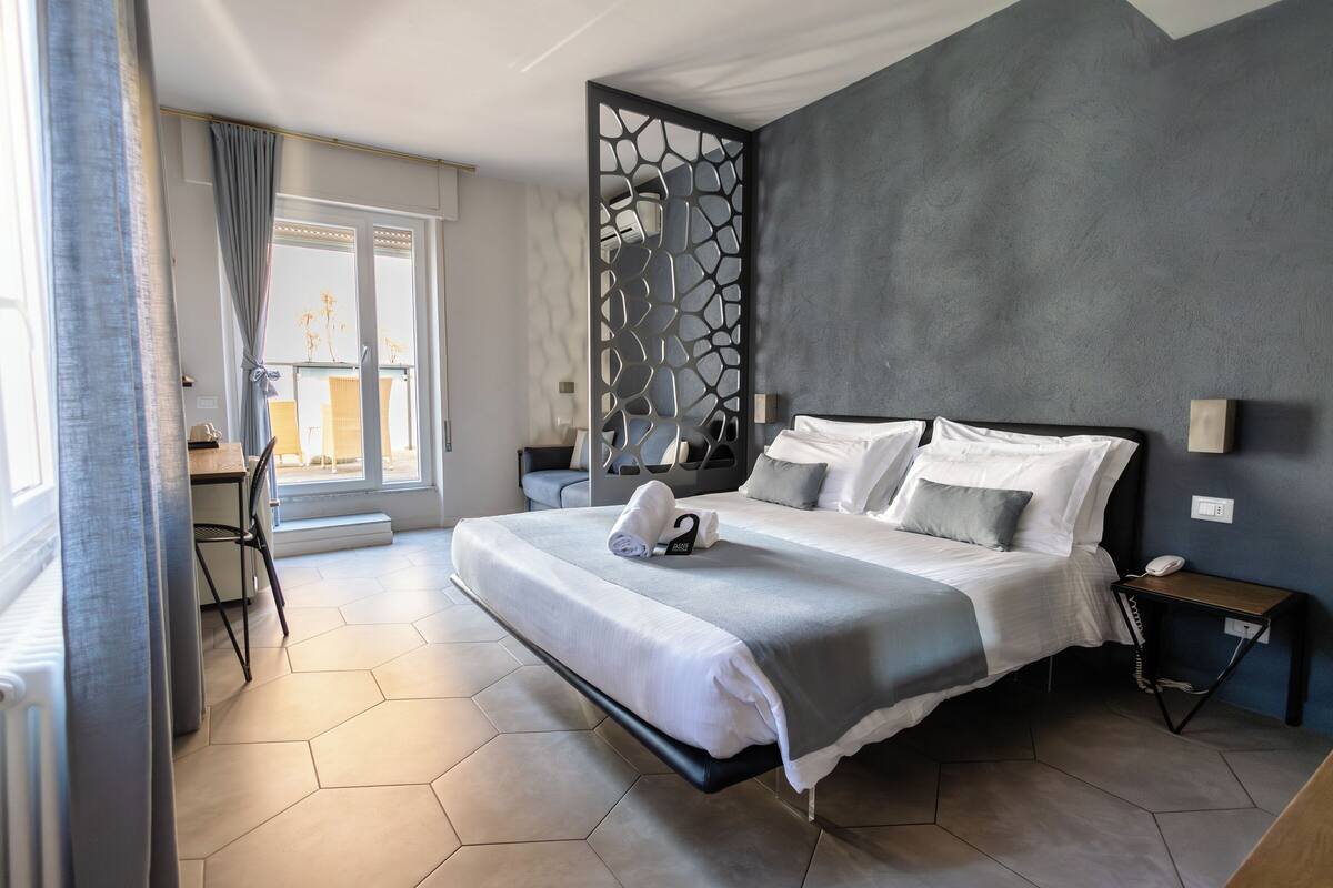 Una habitación de hotel moderna con una cama grande, un escritorio y vistas a la ciudad.
