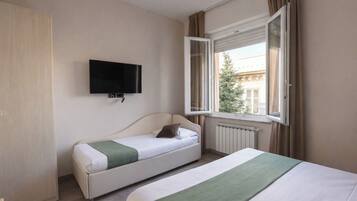 Una habitación de hotel con cama, sofá cama, televisor y ventana con cortinas.