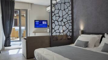 Et moderne hotelværelse med seng, sofa, TV og udsigt til altan.