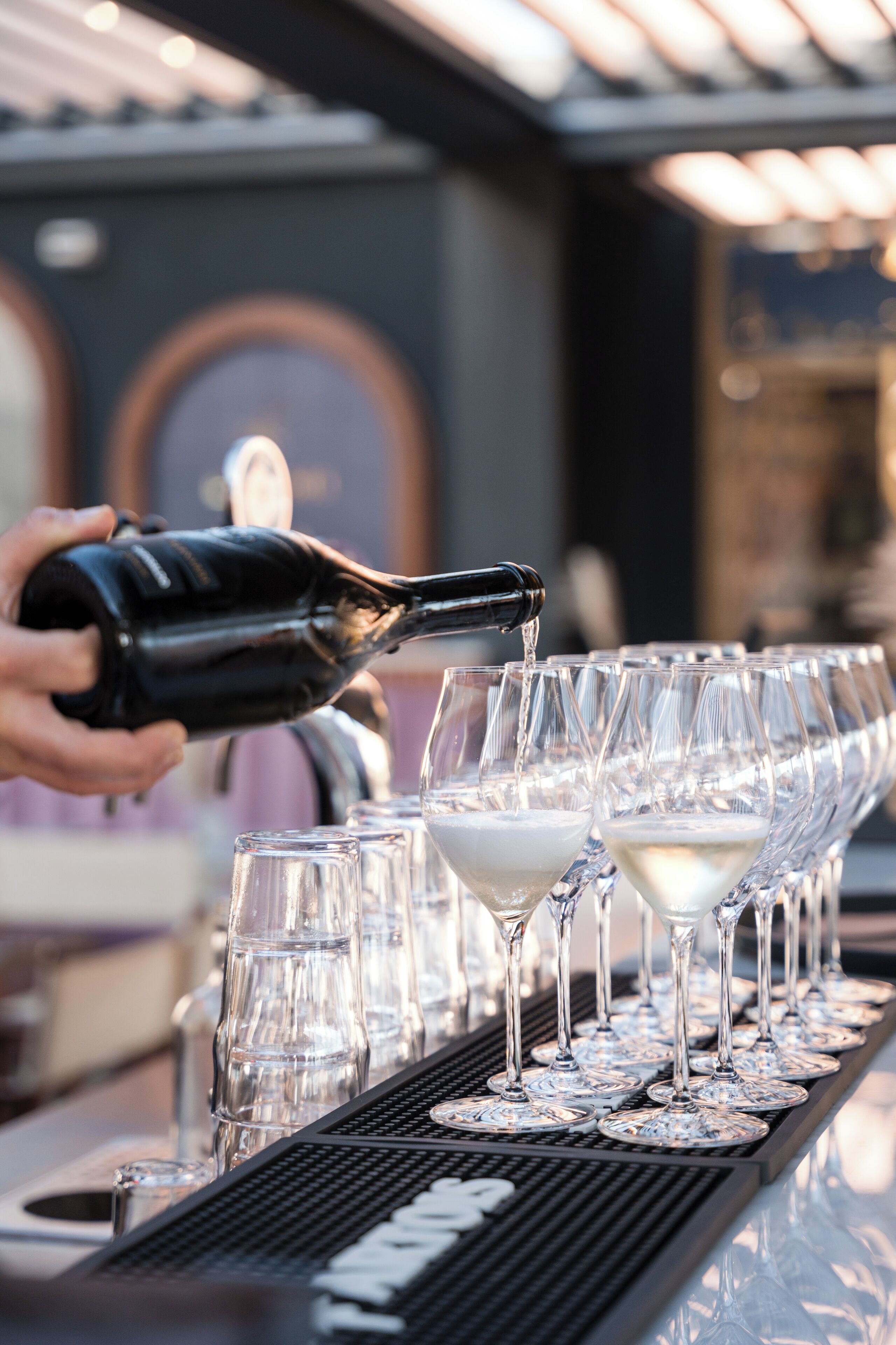 A bar setting with a bottle being poured into glasses.