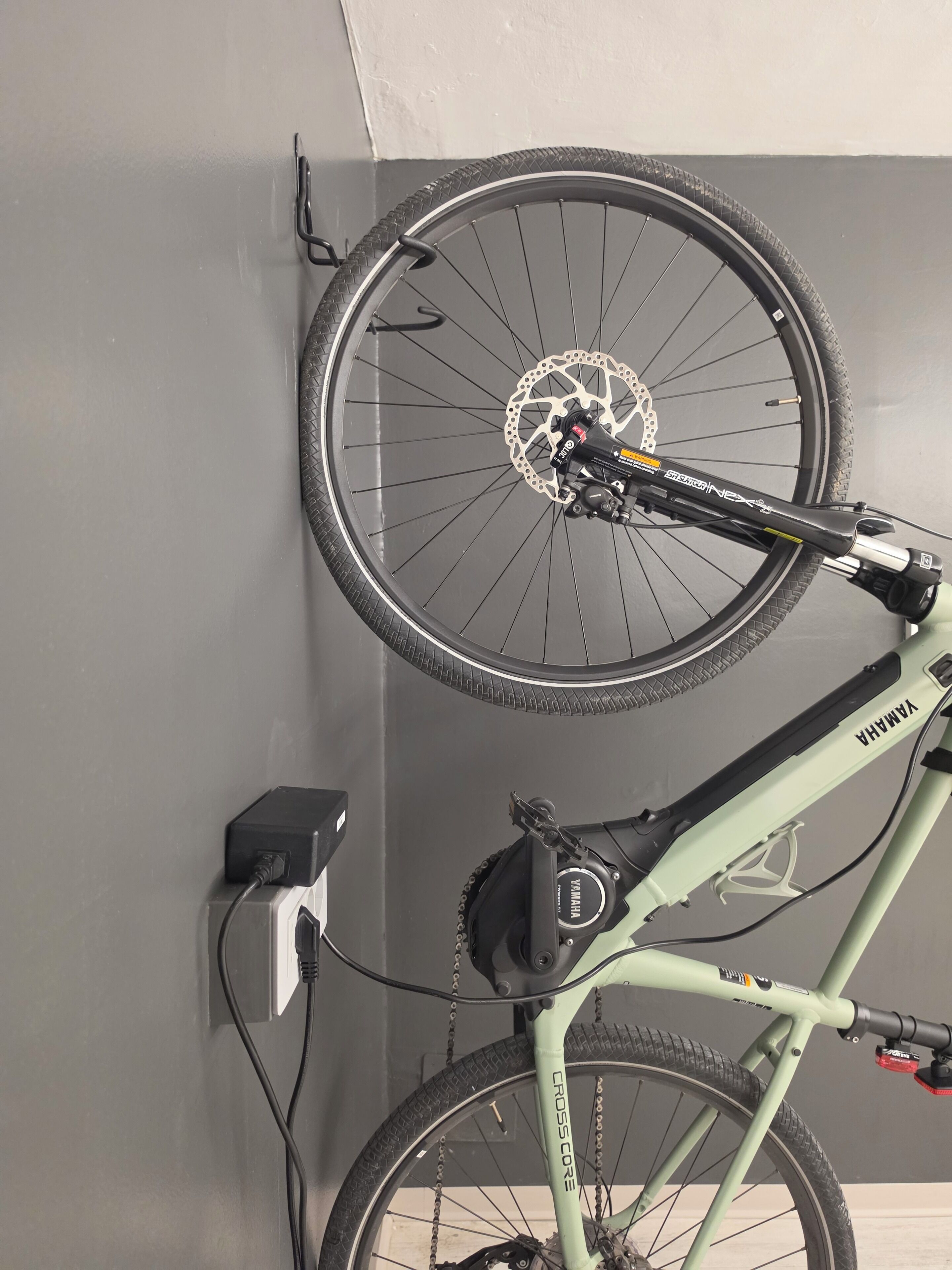 Un vélo équipé d’un système de transmission Shimano et de freins à disque Shimano, fixé au mur près d’une prise de courant.