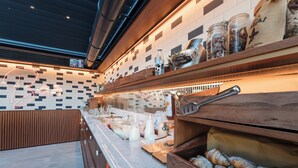 A breakfast buffet area with a marble counter, wooden shelves, and a variety of food items. - Albergo Stella Del Mare (Chiavari)