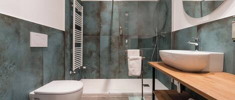Une salle de bain moderne avec un grand lavabo blanc, une douche à parois de verre et des toilettes.