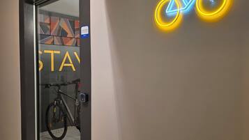 A hotel corridor with a neon bicycle sign, a glass door with a bike rack, and a 'STAY' sign.