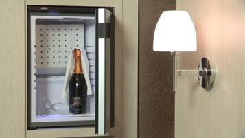 A minibar with a bottle of champagne and a glass.