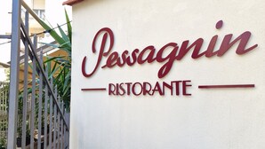 A sign for "Pessagnin Ristorante" with a stone and rock border and a metal railing. - Albergo Stella Del Mare (Chiavari)
