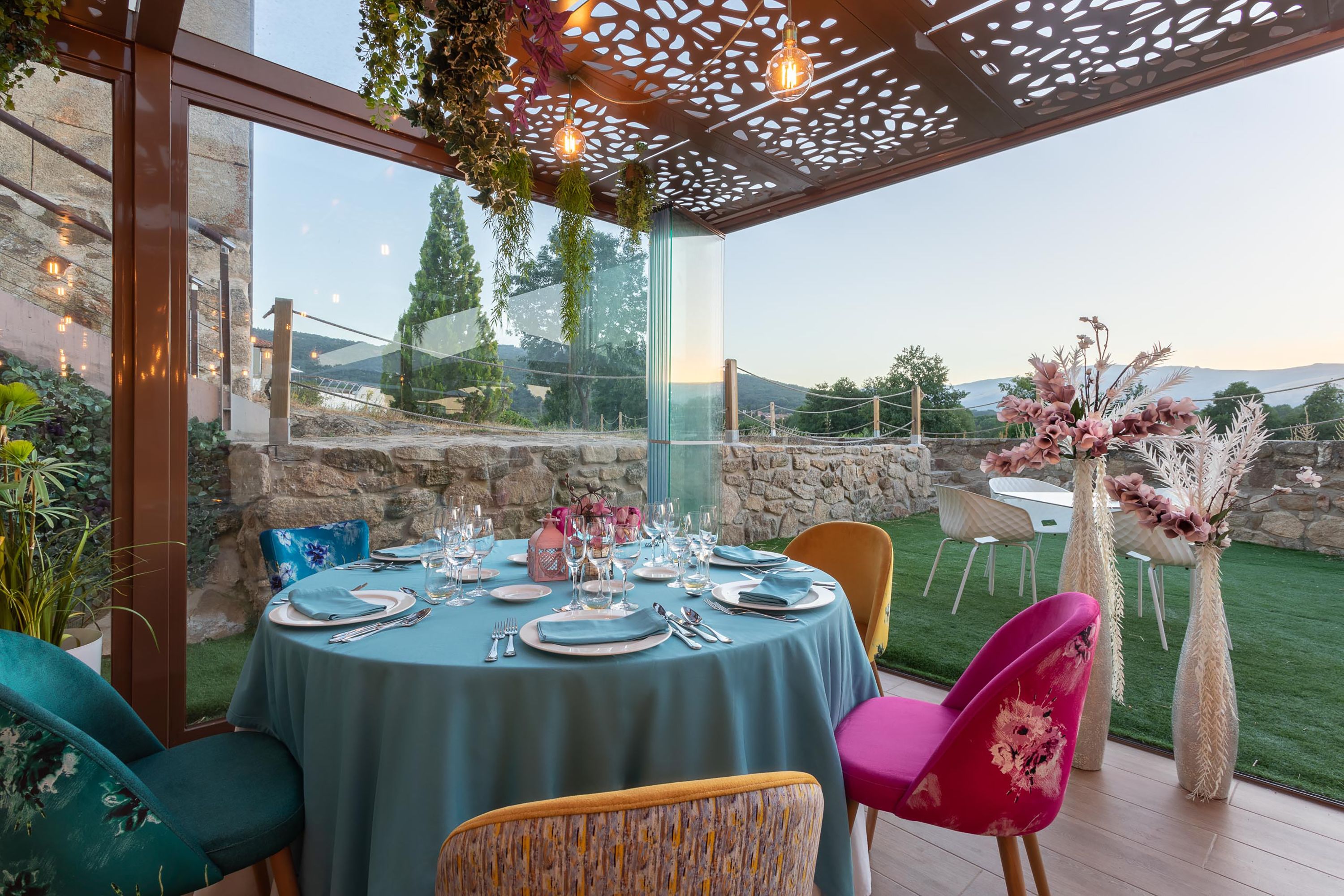 An outdoor dining area with a round table set for four, surrounded by chairs with floral upholstery.