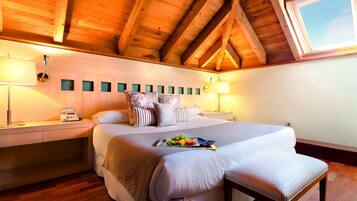 Un dormitorio con techo de madera, una cama con múltiples almohadas, mesitas de noche con lámparas y una ventana.