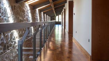 A long corridor with wooden flooring and a stone wall on one side.