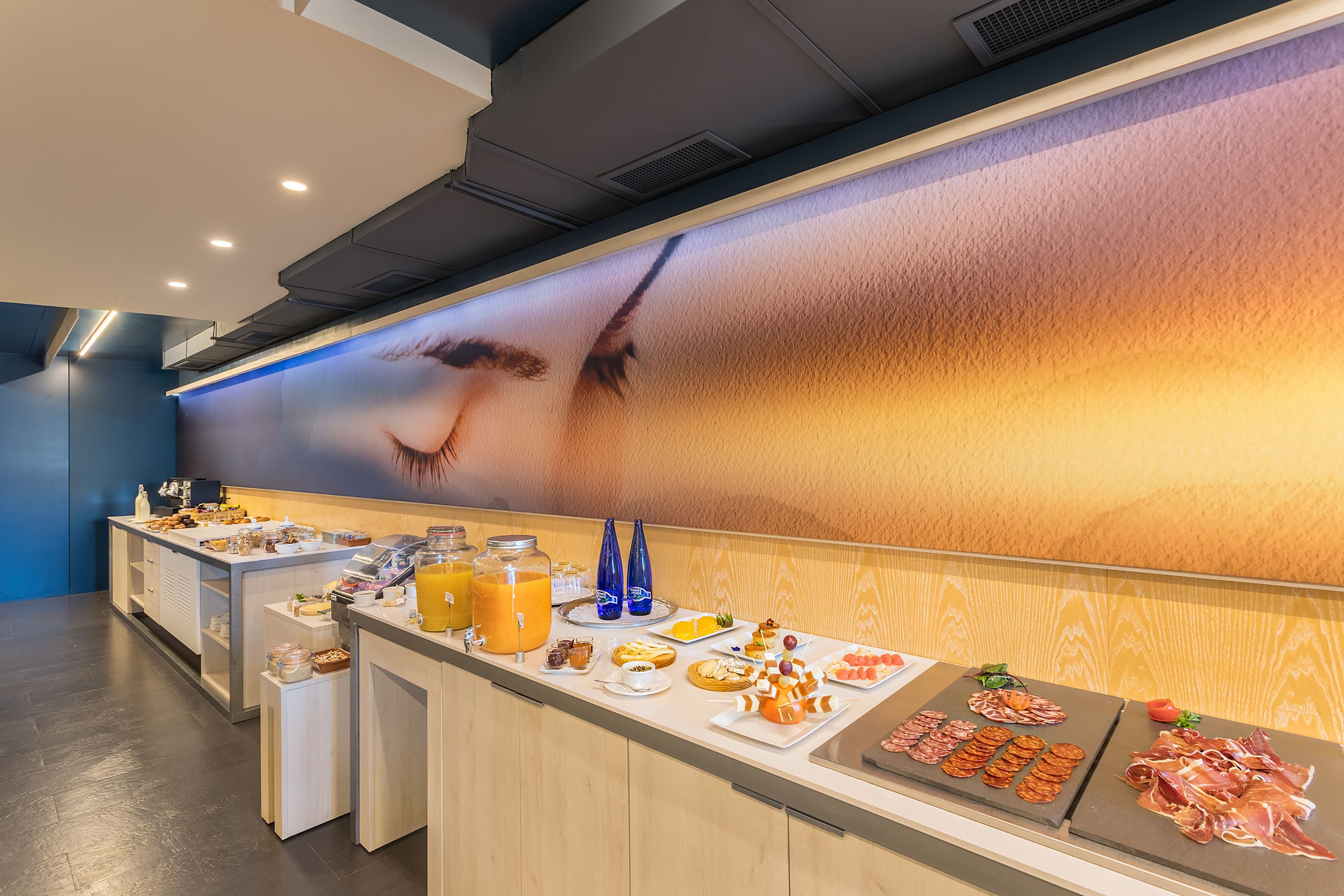 Un bufé de desayuno con diversas opciones de comida y un amplio mural en la pared.