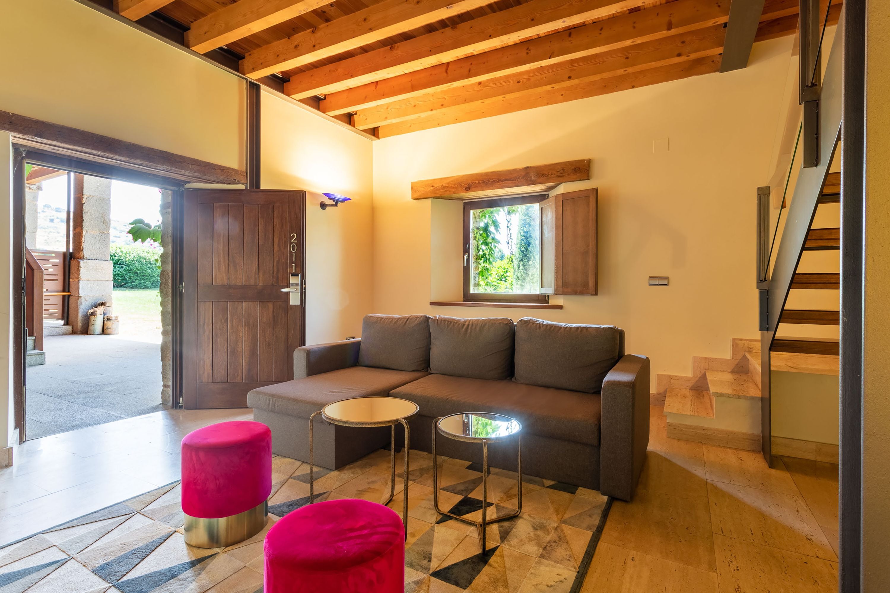 Una sala de estar moderna con un sofá, dos mesitas y una escalera.