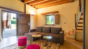 Una sala de estar moderna con un sofá, dos mesitas y una escalera.