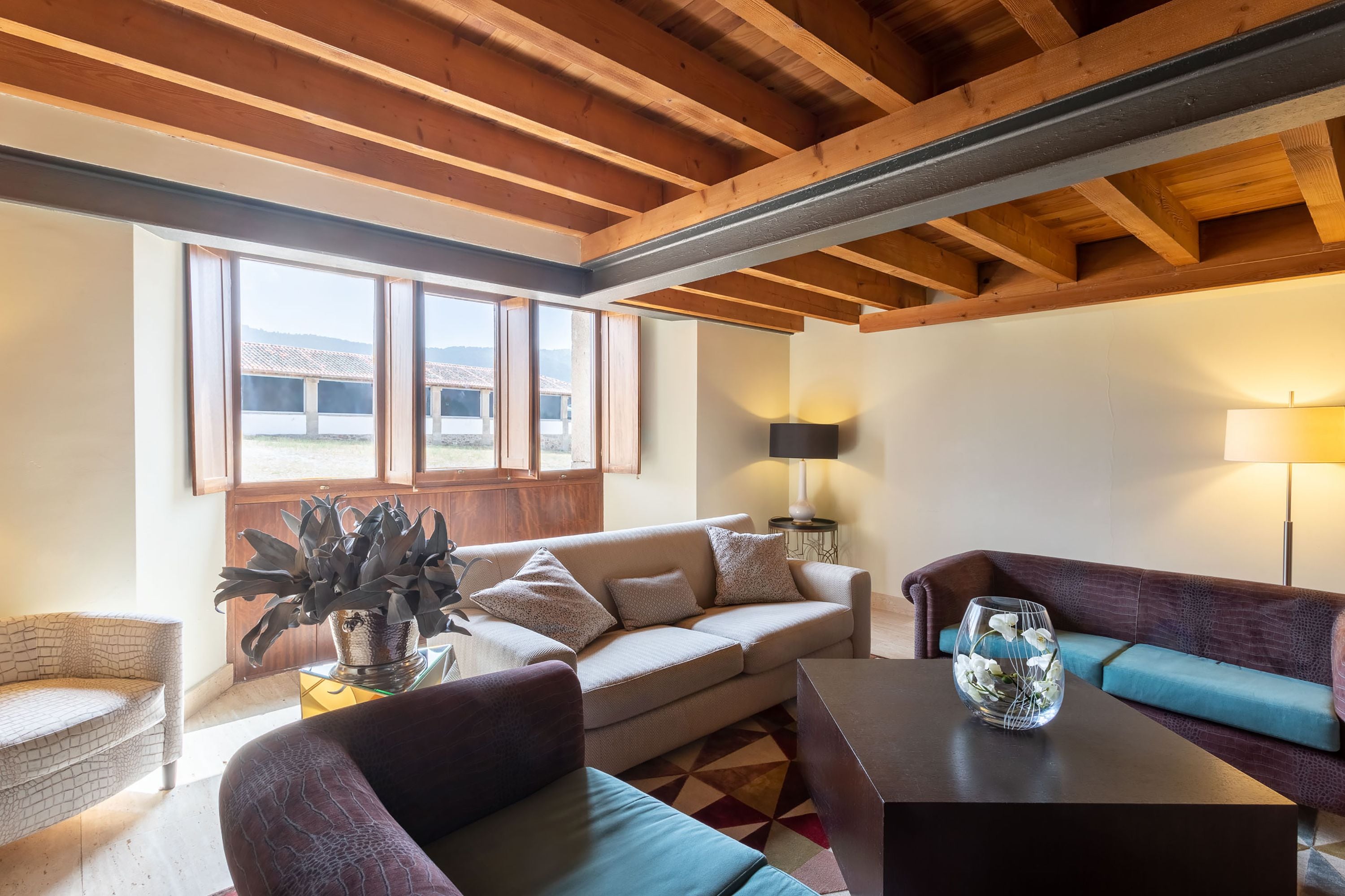 Una sala de estar con un sofá, sillones, una mesita de centro y una planta en maceta.