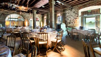 A restaurant with round tables, wooden chairs, and string lights.