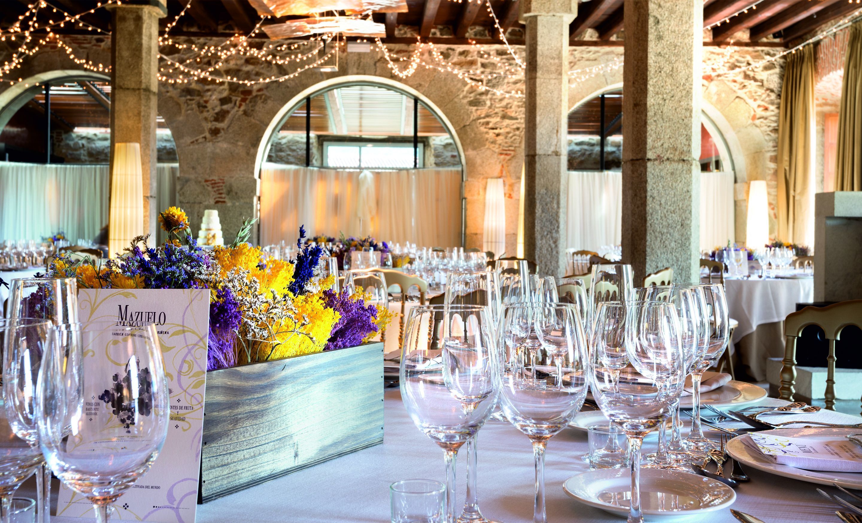 A banquet hall with tables set for a formal event, featuring clear glassware and floral centerpieces.