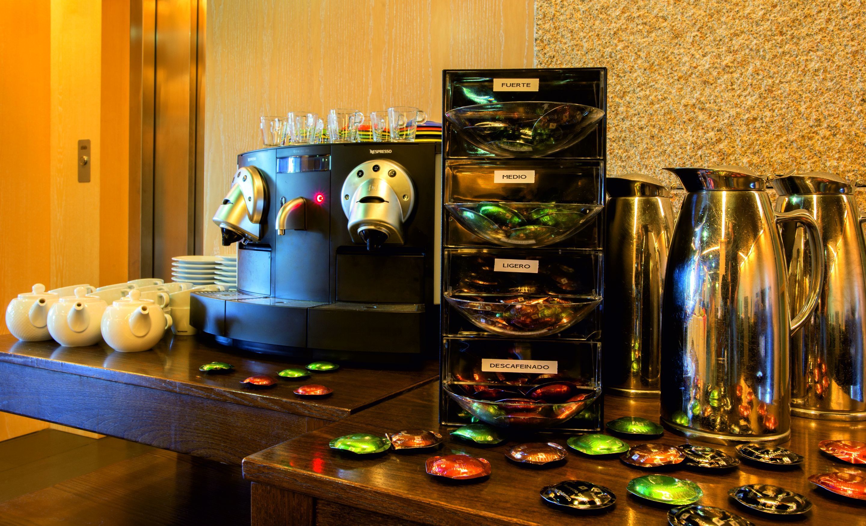 Eine Kaffeestation mit einer Nespresso-Maschine, verschiedenen Kaffeetassen und einer Auswahl bunter Kaffeekapseln.