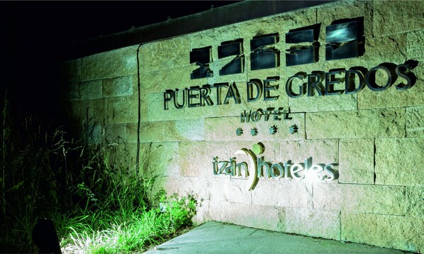 Un muro de piedra con el texto "PUERTA DE GREDOS HOTEL" y "izn hotels", indicando el nombre del hotel.