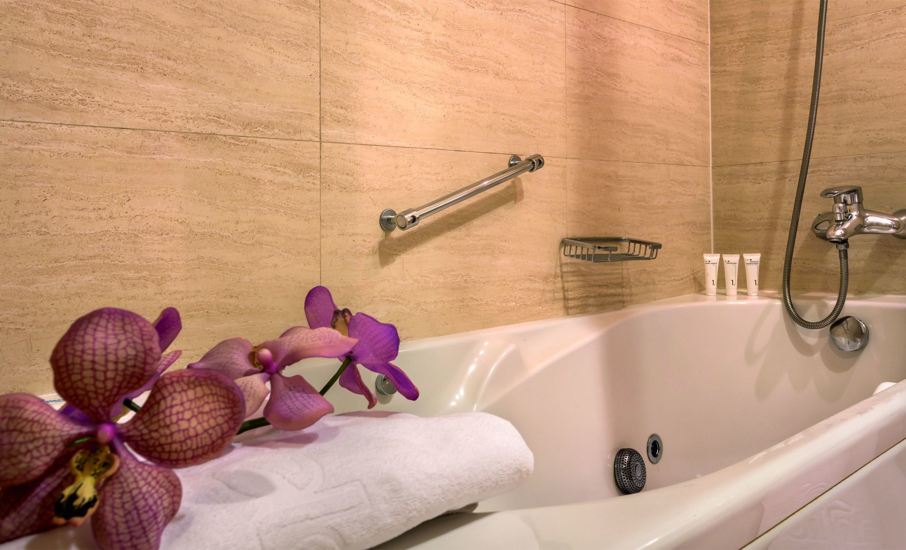 A bathroom with a bathtub, a shower, a towel rack, and a small shelf with toiletries.