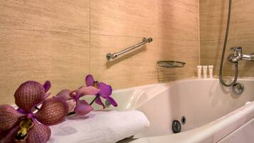 A bathroom with a bathtub, a shower, a towel rack, and a small shelf with toiletries.