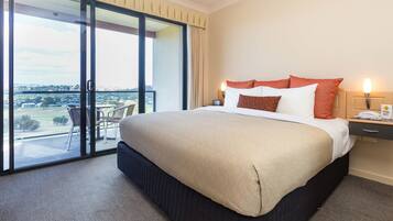 A hotel room with a large bed, a nightstand with a phone, and a view of the outdoors through a sliding glass door.