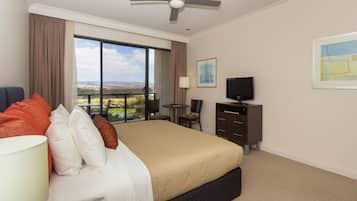 Habitación de hotel con cama, escritorio, silla, televisión y vista al paisaje.