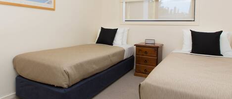 A hotel room with two beds, a nightstand, a window with blinds, and a painting on the wall.
