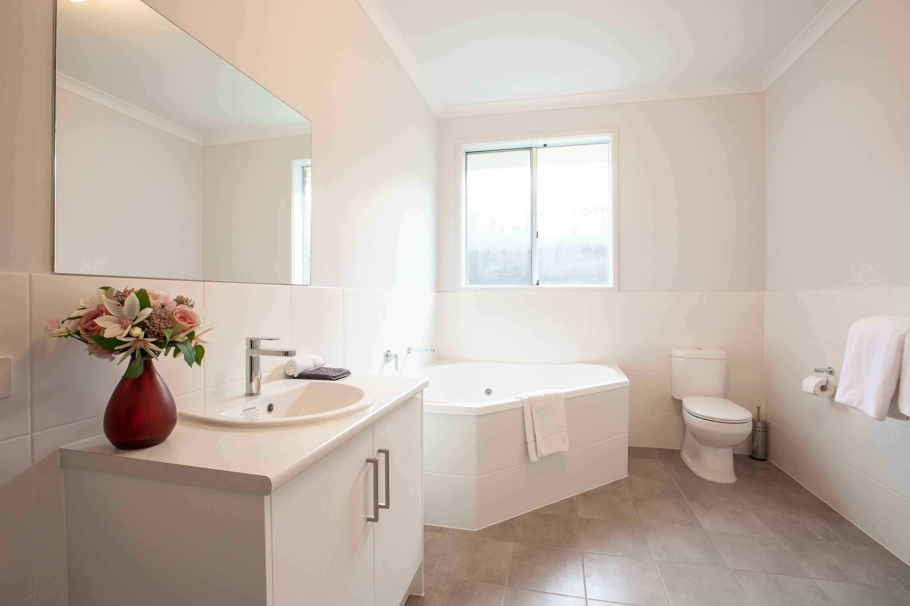 A modern bathroom with a large mirror, a sink, a bathtub, and a toilet.